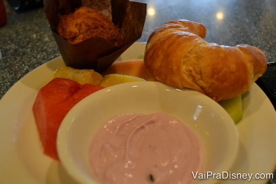 Foto de um prato com um croissant, iogurte de morango e um muffin 