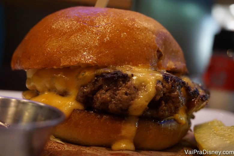 O cheeseburger do Felipe, acompanhado de picles e batatas fritas  