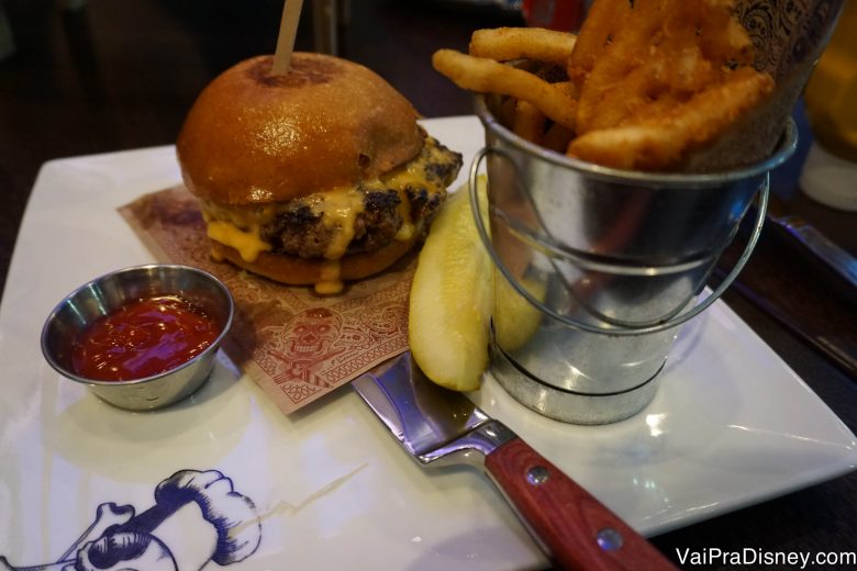 O cheeseburger do Felipe, acompanhado de picles e batatas fritas  