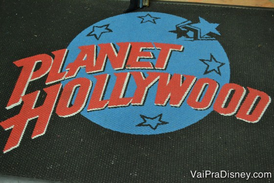 O símbolo do Planet Hollywood, azul e vermelho, no cardápio de fundo preto 