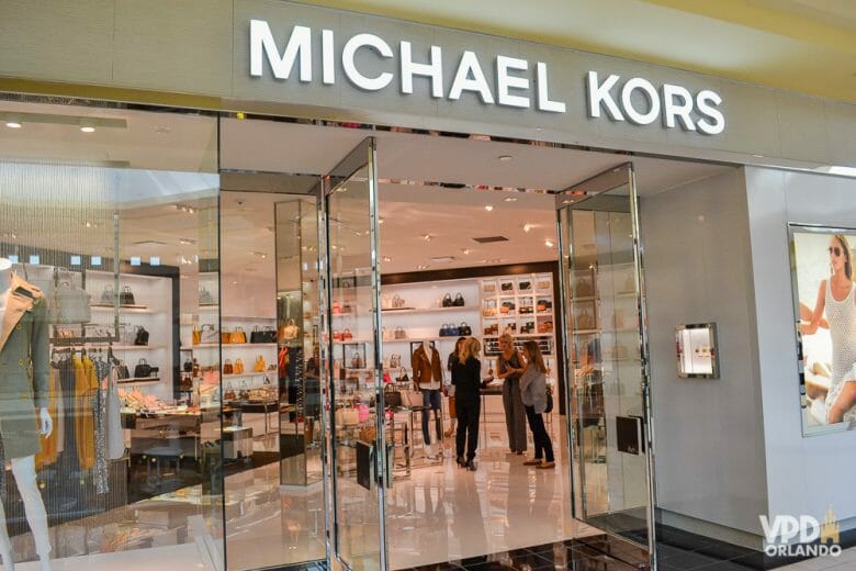 Vitrine de bolsas na Michael Kors. As mulheres piram e gostam muito de gastar nessa loja! Foto da vitrine da loja Michael Kors, com algumas roupas à vista. 