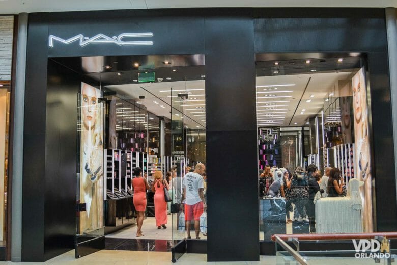 Vale checar os valores da MAC aqui no Brasil e ver se compensa comprar em Orlando! Foto da vitrine da loja da MAC em Orlando, com alguns visitantes dentro. 