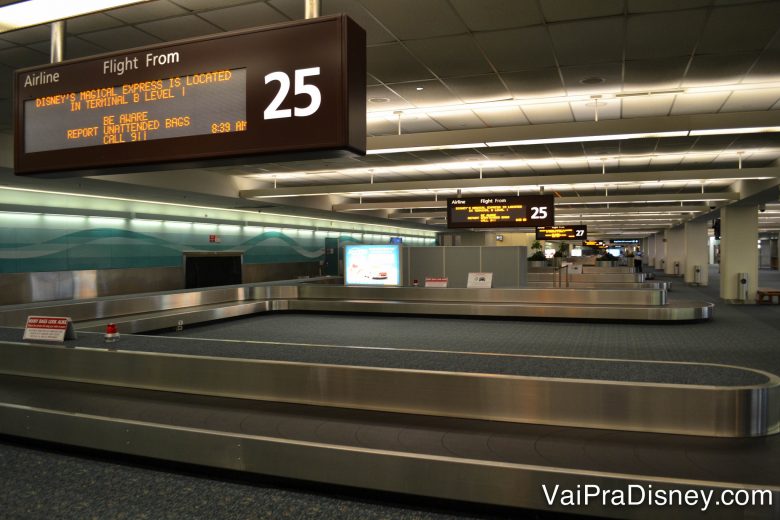 Foto da esteira de bagagem no aeroporto de Orlando, com a placa indicando as informações dos voos acima. 