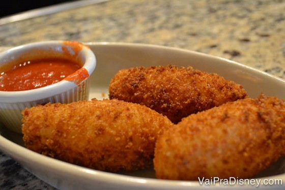 Foto do bolinho de arroz recheado de mussarela acompanhado de um molho de tomate bem temperado. 