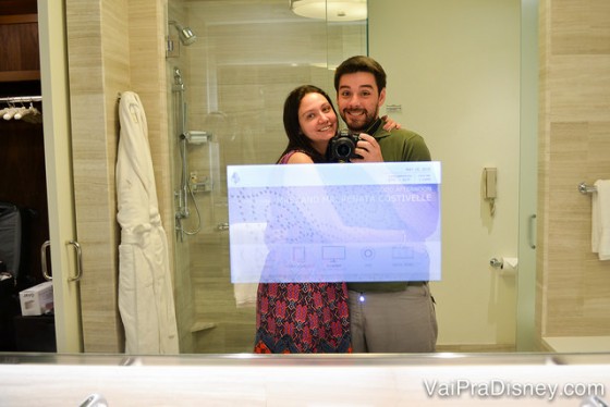 Foto da Renata e do Felipe no espelho do banheiro, mostrando que ele tem uma TV no meio 