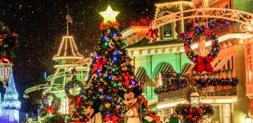 Foto da parada de Natal do Magic Kingdom, com o Mickey em cima do carro com uma árvore de Natal atrás dele, e a Main Street toda iluminada ao redor