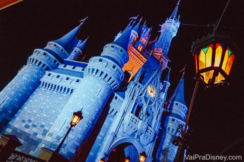 Foto do castelo da Cinderela de perto, à noite. Ele está iluminado em azul e o céu atrás está escuro. 