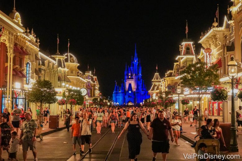 A medição de temperatura pode se tornar um procedimento padrão. Foto do Magic Kingdom em um dia cheio, com o castelo da Cinderela iluminado em azul ao fundo, o céu noturno escuro e as luzes da Main Street acesas 