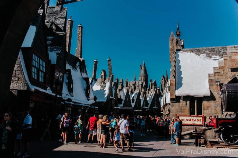 O Beco Diagonal é o mais recente, mas Hogsmeade também é linda e cheia de detalhes para os fãs. Foto de Hogsmeade, com as construções cobertas de neve falsa e o céu azul ao fundo. 