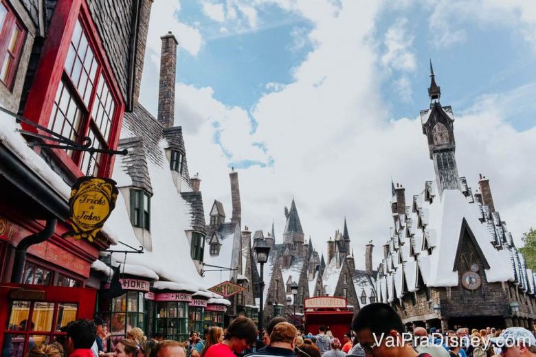 Foto de Hogsmeade, na Universal, com as construções cobertas de neve falsa e o céu azul ao fundo. 