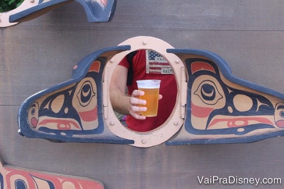 Foto de uma mão segurando a cerveja no lugar de colocar o rosto para tirar foto no pavilhão do Canadá 