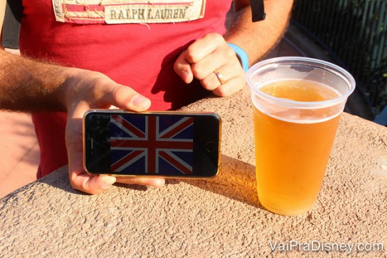 Foto do drinque ao lado da bandeira do país no celular, que o amigo da Rê tirou para manter organizado. No caso, uma bandeira do Reino Unido ao lado de um copo de cerveja 