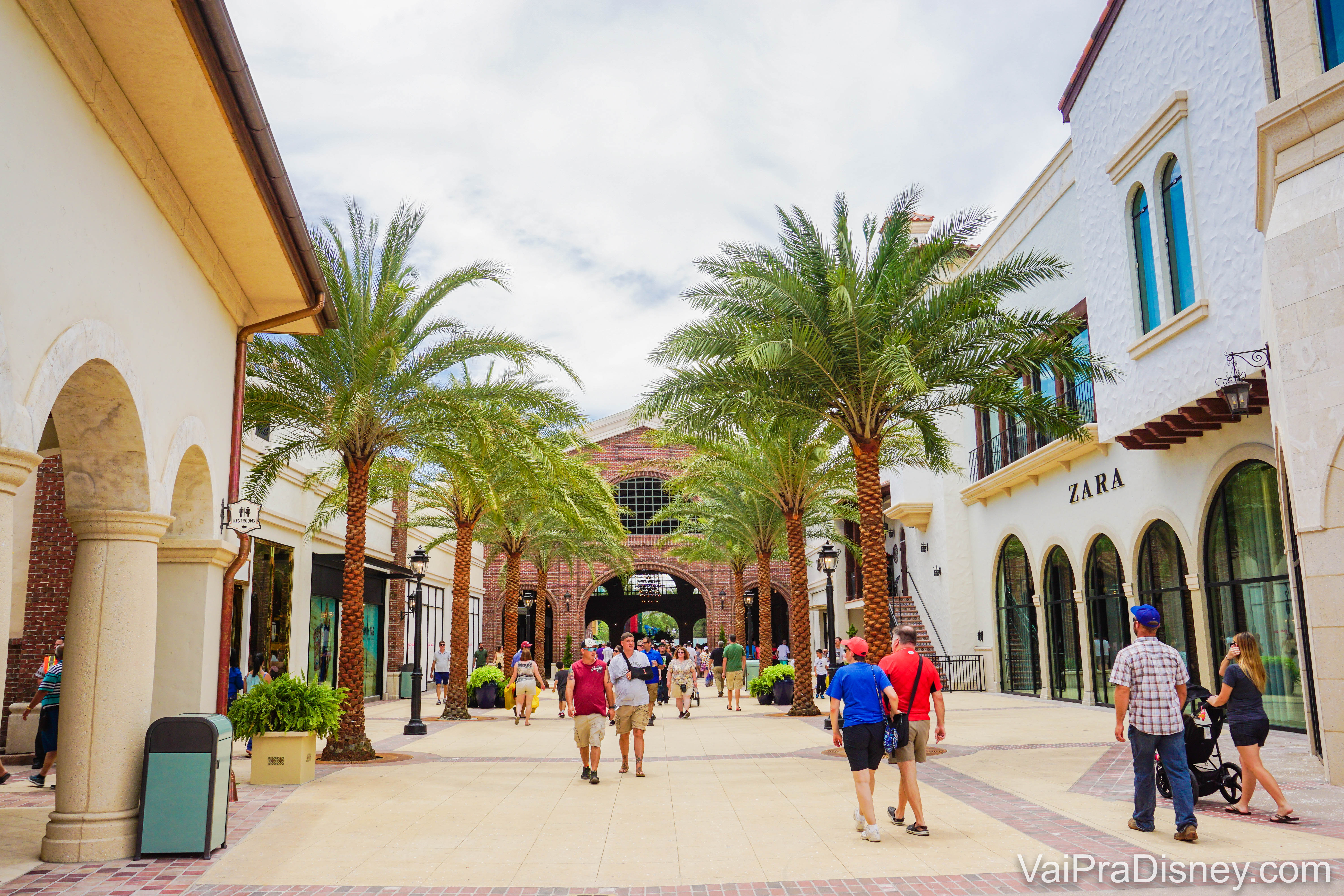 Imagem da área externa das lojas em Disney Springs, com árvores ao redor. É possível ver a loja da Zara à direita. 