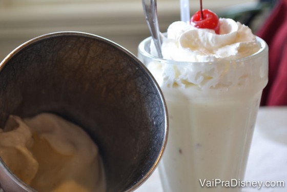 Foto do milkshake na taça com cereja em cima servido no The Plaza Restaurant do Magic Kingdom, com o copo com o restinho que é servido junto 