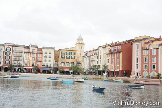 Foto do Portofino Bay durante o dia, com o lago, barcos passando e as lojas e restaurantes mais ao fundo 