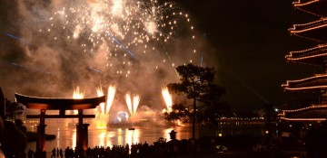 Foto do show de fogos Illuminations, no Epcot, em que os fogos são lançados de dentro do lago. É possível ver o portal do pavilhão do Japão e os fogos explodindo atrás.