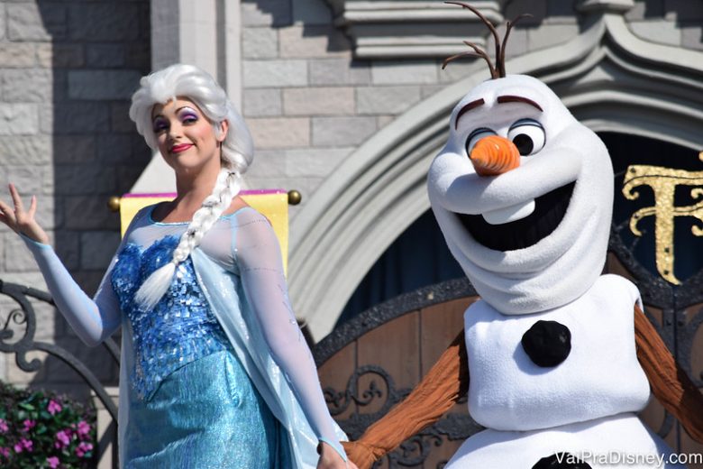 Personagens de Frozen se juntam aos clássicos para o show em frente ao castelo. Foto de Elsa de mãos dadas com Olaf em frente ao castelo da Cinderela no Magic Kingdom 