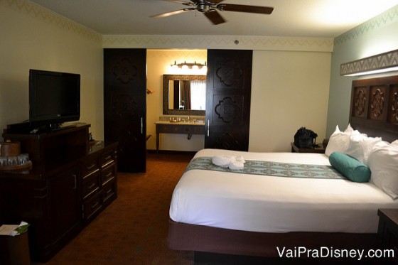 Foto do quarto antes da reforma, com a cama king, carpete e móveis de madeira escura 