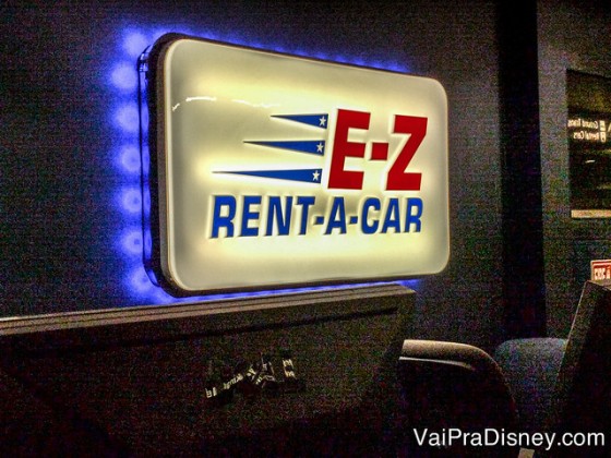 Placa da locadora de carros E-Z Rent-A-Car no aeroporto de Orlando, com fundo branco e letras em vermelho e azul 