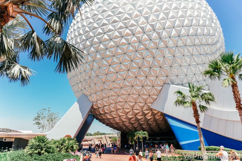 Imagem que mostra a bola do Epcot em um dia de céu azul, com visitantes passando embaixo e ao redor dela. 