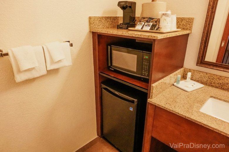 Parte da mini cozinha do quarto padrão, com um frigobar, cafeteira e microondas.