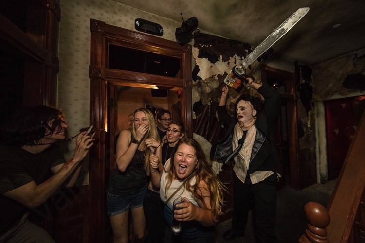 Foto da festa de Halloween da Universal. que mostra visitantes sendo assustados pelo personagem Leatherface, do Massacre da Serra Elétrica. 