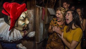 Foto de visitantes levando um susto com um personagem mascarado na Halloween Horror Nights da Universal