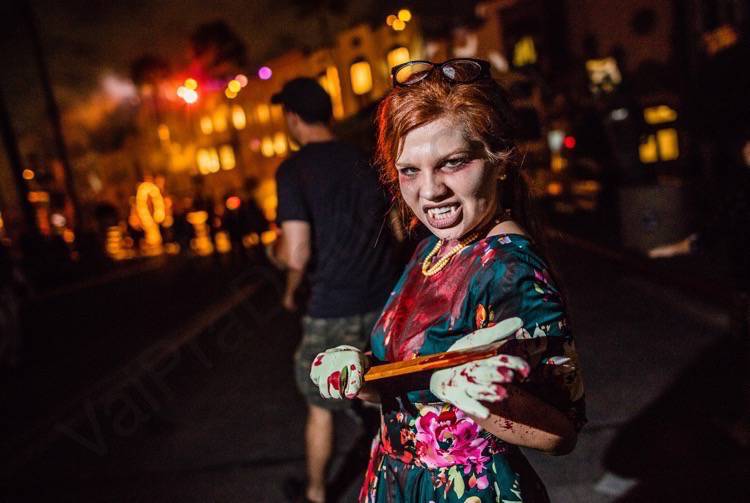 Halloween Horror Nights da Universal. Imagem de uma personagem com a roupa coberta de sangue, com um pedaço afiado de madeira nas mãos e dentes de vampiro. 