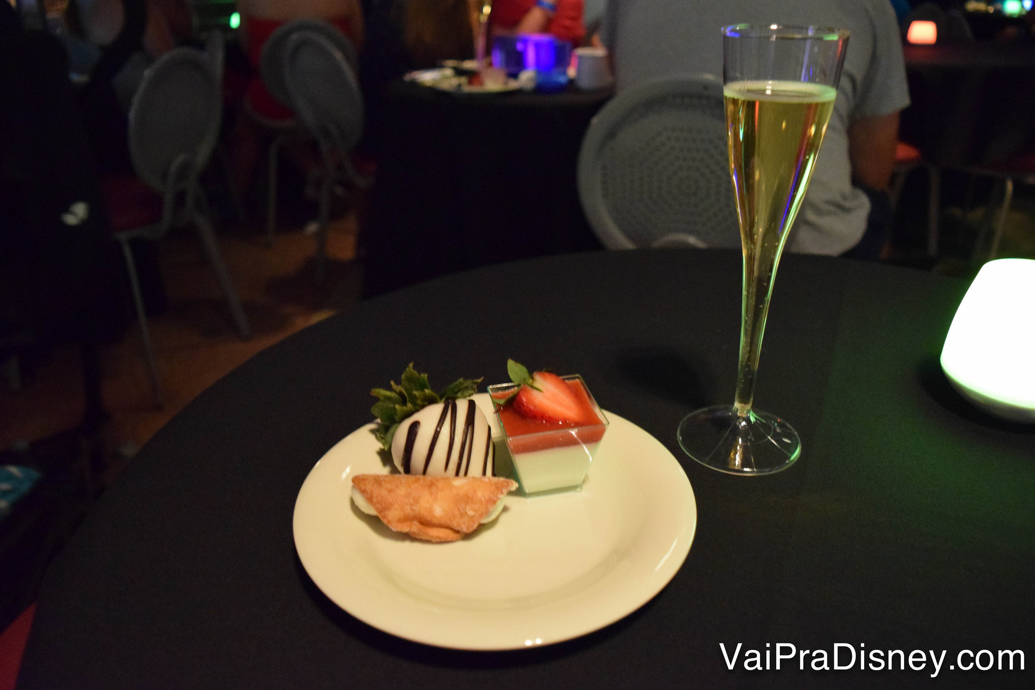 Foto dos docinhos e do champagne sobre a mesa 