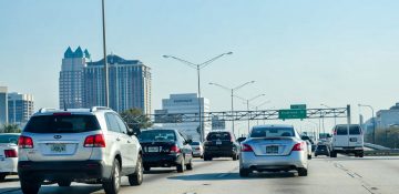 Foto da rodovia em Orlando, com diversos carros à frente e o céu claro ao fundo.