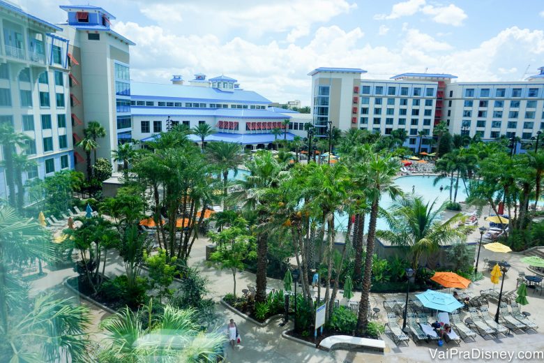 Foto da área externa do Loews Sapphire Falls Resort, mostrando o prédio branco com detalhes em azul e parte da área da piscina, com palmeiras em volta 