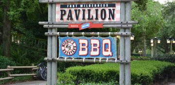 Foto da placa na entrada do Mickey's Backyard BBQ no Fort Wilderness, com fundo azul e um Mickey no centro