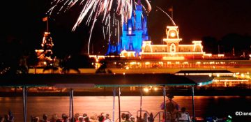 Foto dos fogos do Magic Kingdom, com o castelo e o parque iluminados ao fundo, tirada do barco do Pirates & Pals Fireworks Voyage