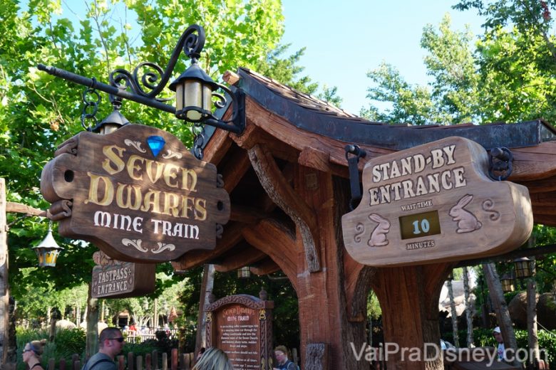 Foto das placas de madeira indicando a entrada da Seven Dwarfs Mine Train. O display digital mostra 10 minutos de fila sem Fastpass (stand-by entrance)