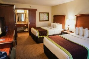 Foto do quarto do Clarion Inn Lake Buena Vista, com duas camas de casal e a pia do banheiro à vista no fundo.