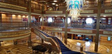 Foto do átrio do Disney Dream, navio em que é feito o cruzeiro pelas Bahamas, com uma escadaria e um lustre elegantes