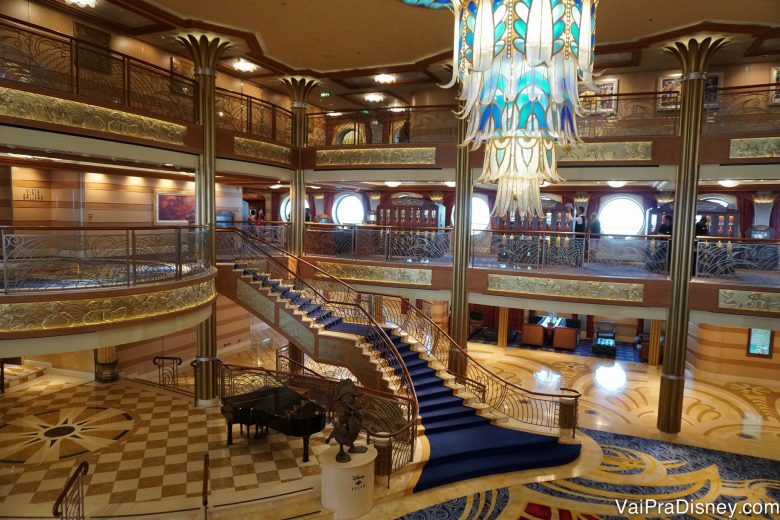 Foto do átrio do Disney Dream, com uma escadaria e um lustre elegantes 