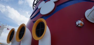 Foto do navio de cruzeiro da Disney, pintado de vermelho com detalhes que remetem à roupa do Mickey