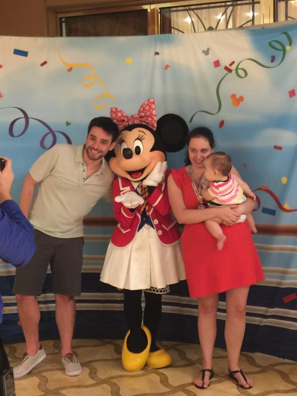 Foto da Renata com a Julia no colo e o Felipe posando para a câmera junto da Minnie 