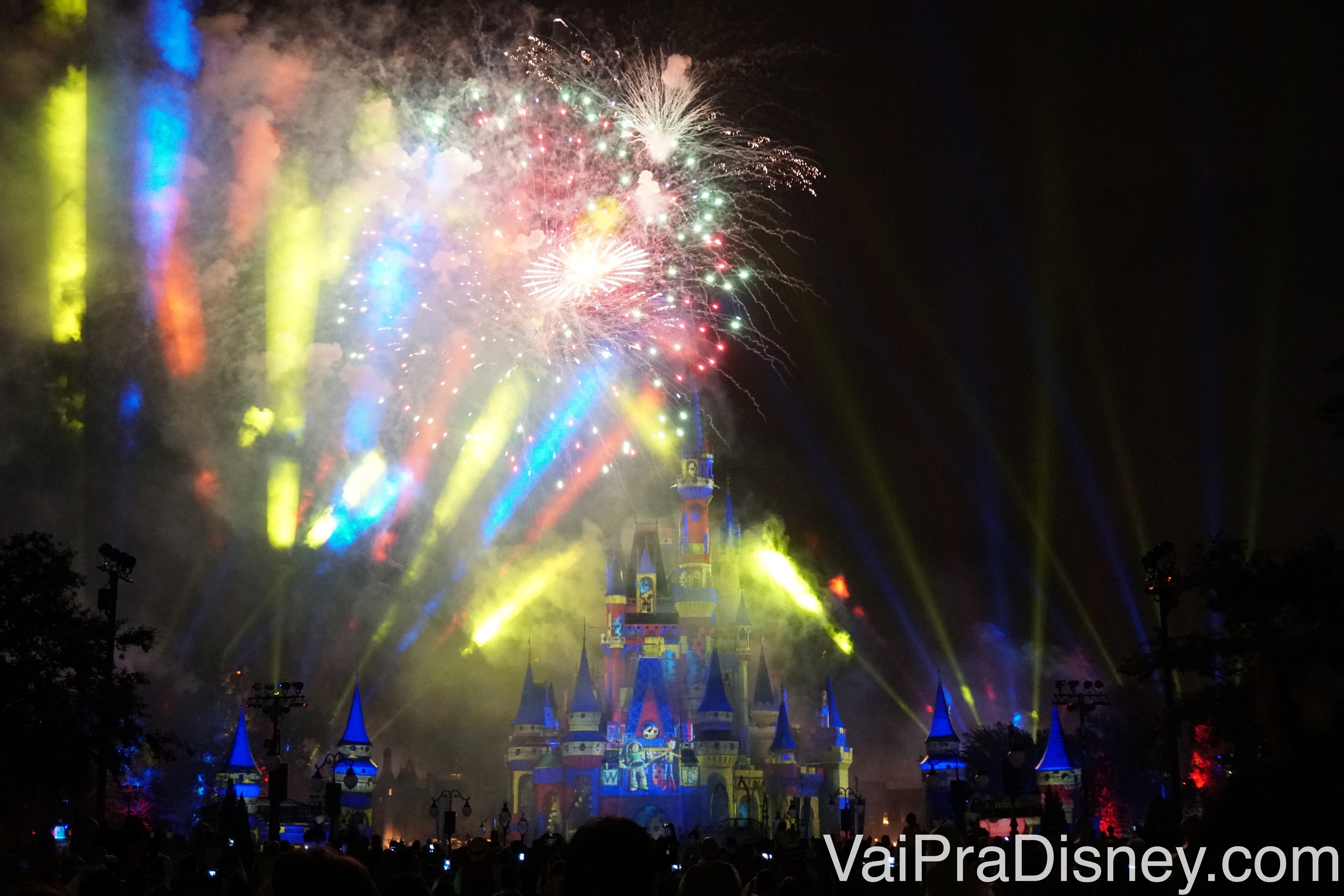 Foto do castelo iluminado em azul com fogos multicoloridos e projeções no céu durante o Happily Ever After 