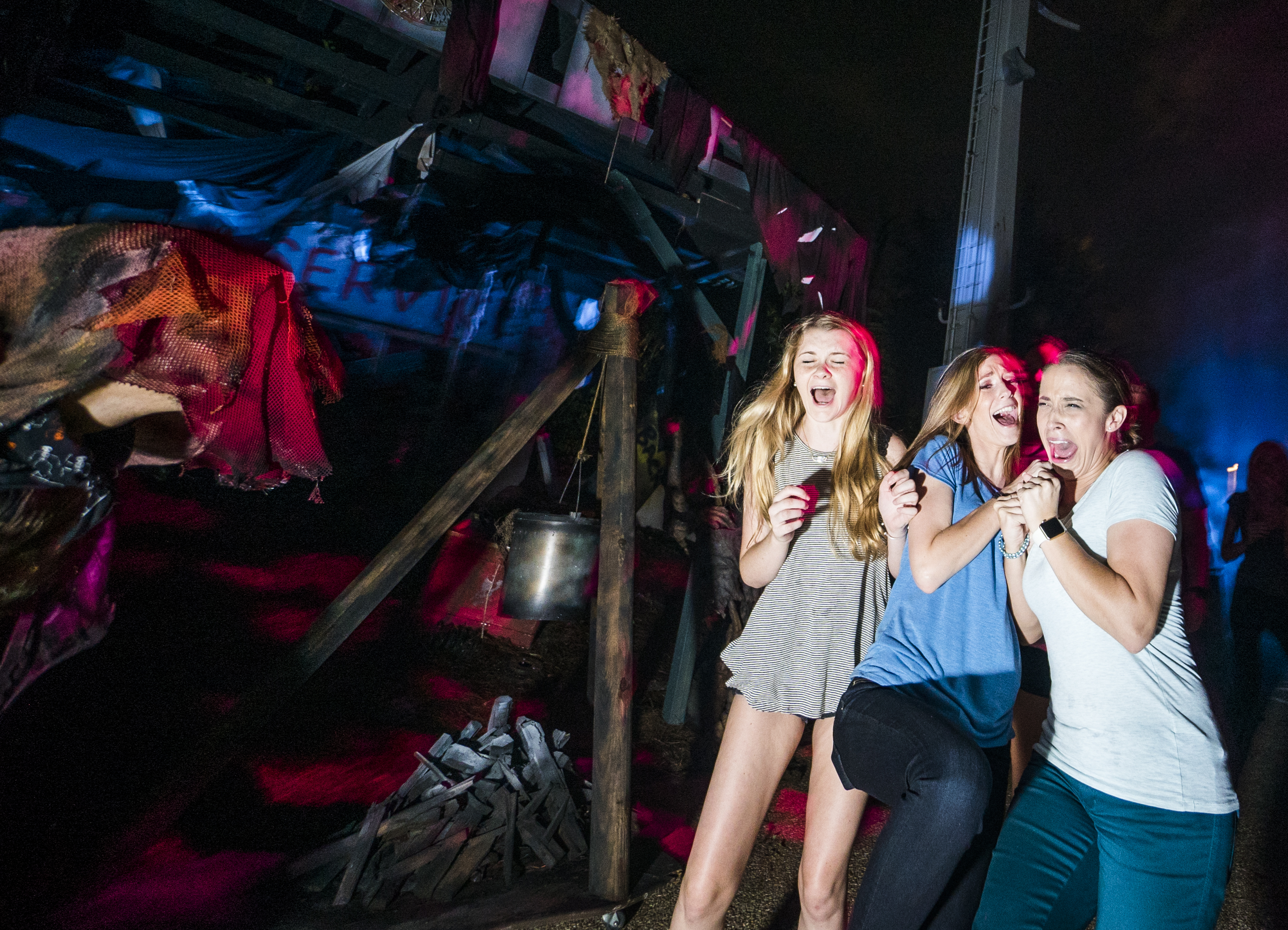 Foto da festa de Halloween do Busch Gardens em que três visitantes estão levando um susto de um personagem indistinto, com a cabeça coberta por um pano. 