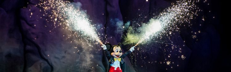Foto do Mickey durante o Fantasmic, segurando tubos que soltam fogos de artifício.