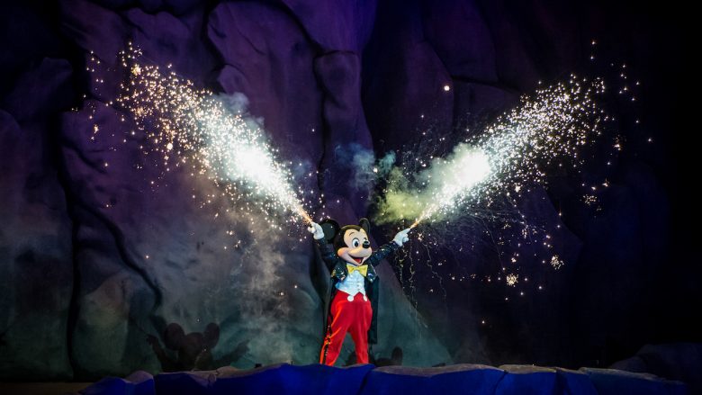 Foto do Mickey durante o Fantasmic, segurando tubos que soltam fogos de artifício. 