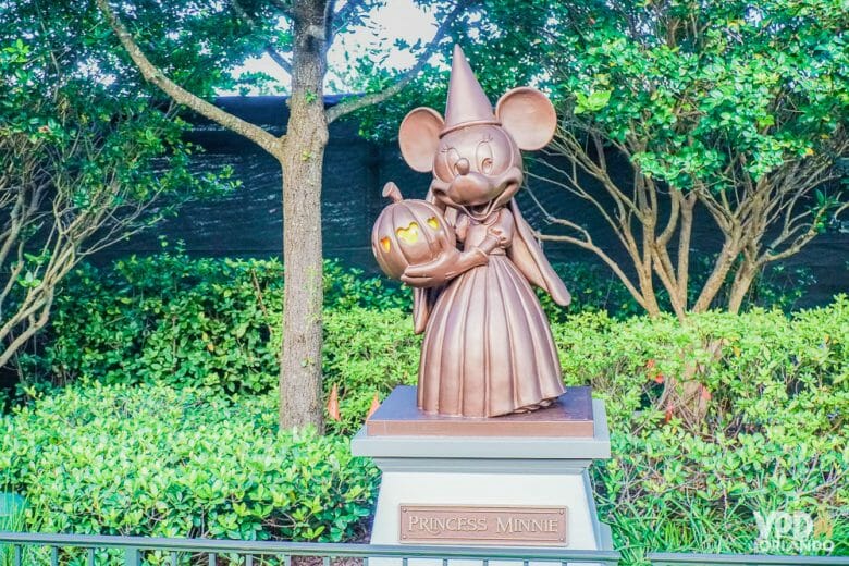 Foto de um dos detalhes temáticos da Festa de Halloween, uma escultura da Minnie vestida de bruxa, com chapéu pontudo e segurando a abóbora-carruagem da Cinderela. 