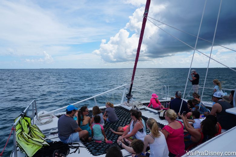 Foto dos visitantes no barco, com uma nuvem escura mas o céu já claro do outro lado. 