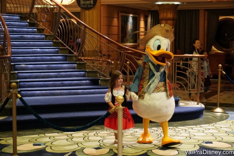 Foto do pato Donald vestido de pirata de mãos dadas com uma menininha durante o cruzeiro 