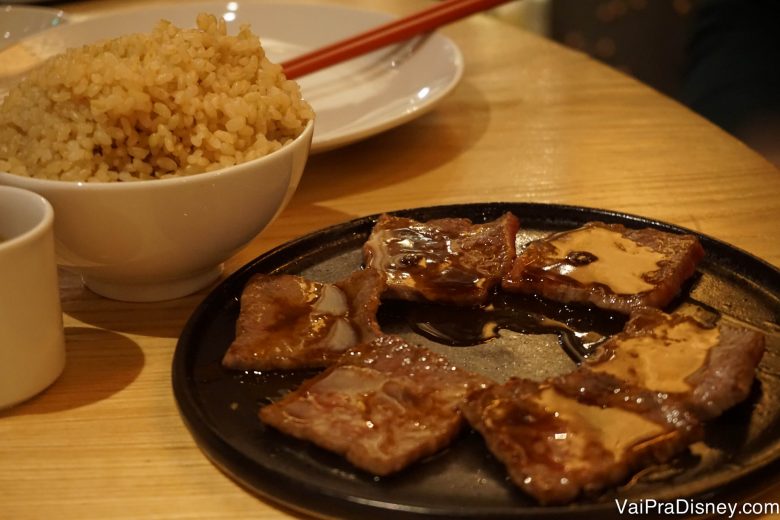 Foto de pedaços de carne sobre um prato e arroz em uma tigela ao lado