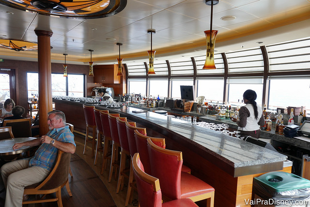 Foto do bar do restaurante Remy no navio, com cadeiras vermelhas e lustres alaranjados 