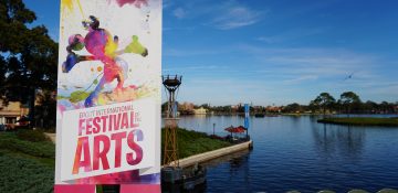 Foto do cartaz do Disney's Festival of the Arts no Epcot, mostrando um Mickey pintado em aquarela em várias cores, com o lago do parque ao fundo.