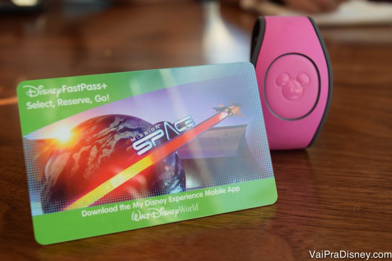 Tão bonitinho, mas tão cheio de regras esse ingresso, né? Imagem do cartão magnético que funciona como ingresso da Disney, ao lado de uma MagicBand cor-de-rosa.